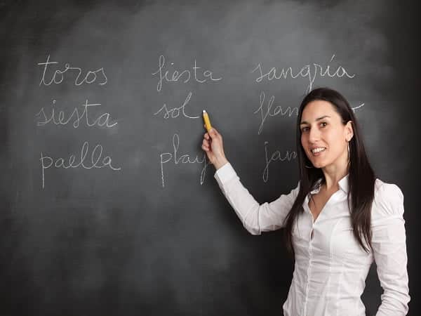 teacher writting on a black board words in spanish